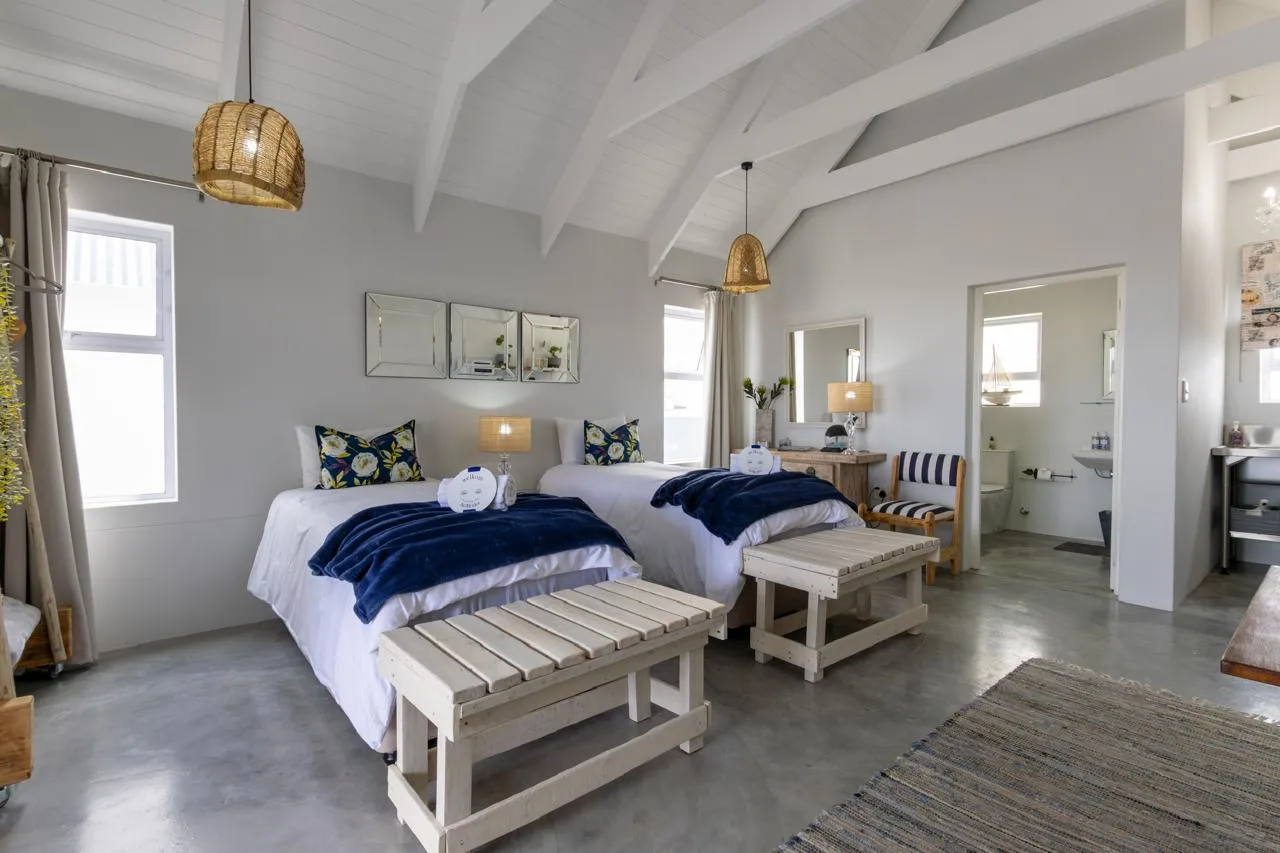 A twin room with rattan lamps, mirrors and an en-suite bathroom