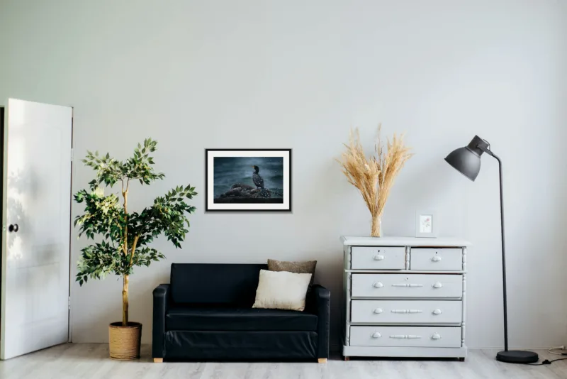 Sea spray shown framed as an A2 print, above a black two-seater between a potted tree and a chest of drawers