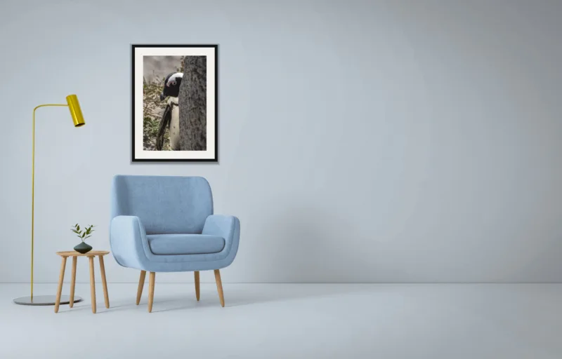 Peekaboo shown framed as an A2 print, above a pale blue armchair on a grey wall