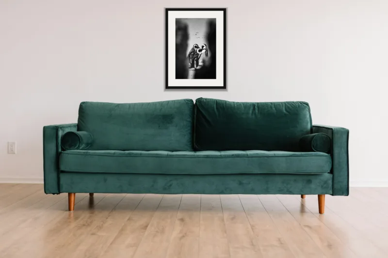 Three’s company shown framed as an A3 print, above a green velvet sofa against a white wall